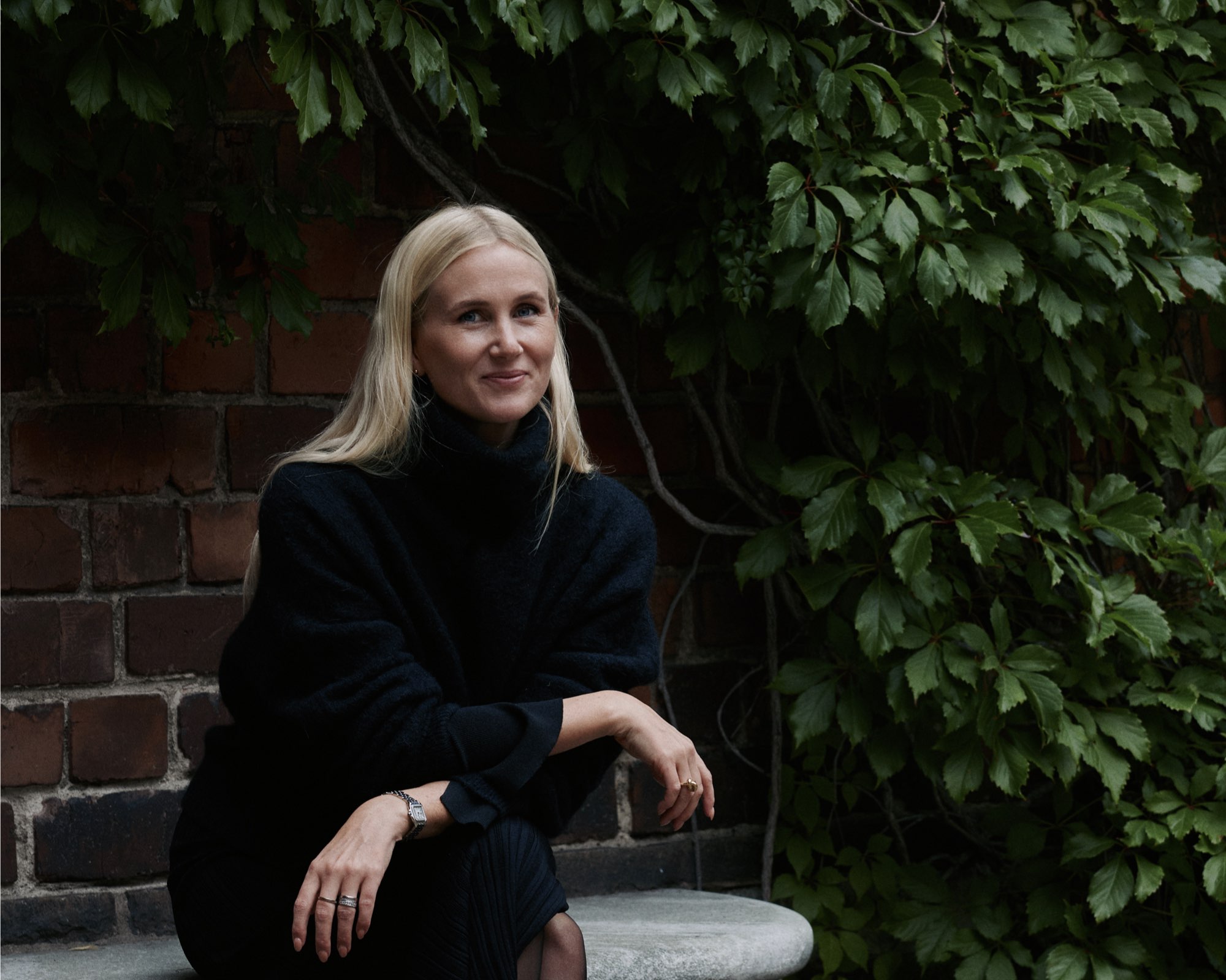Olivia Kukacka sittande intill en mur med grön murgröna